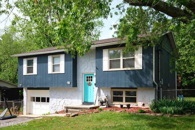 bi-level home featuring fence, a front lawn, concrete driveway, and an attached garage