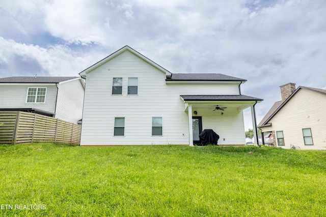 rear view of property with a yard, ceiling fan, and fence