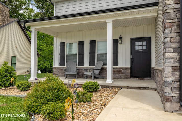 entrance to property with a porch, board and batten siding, and stone siding