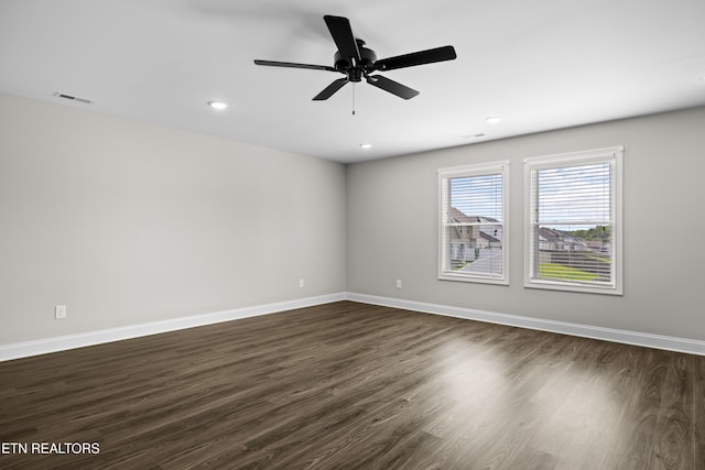 empty room with baseboards, a ceiling fan, and dark wood-style floors