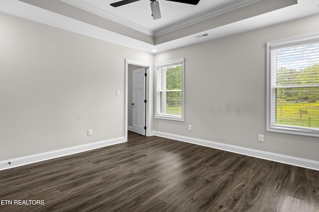 empty room with crown molding, a ceiling fan, dark wood-style flooring, and baseboards