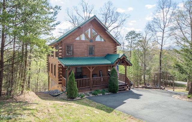 log-style house with a porch, driveway, and log siding