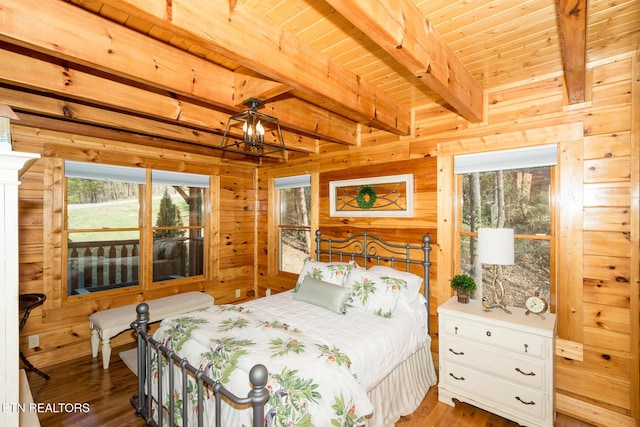 bedroom with wood walls, wood finished floors, and beamed ceiling