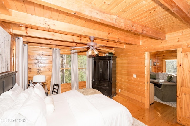 bedroom featuring wood finished floors, wooden walls, and multiple windows