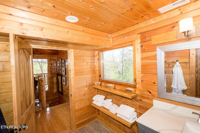bathroom with visible vents, wooden ceiling, wooden walls, wood finished floors, and vanity