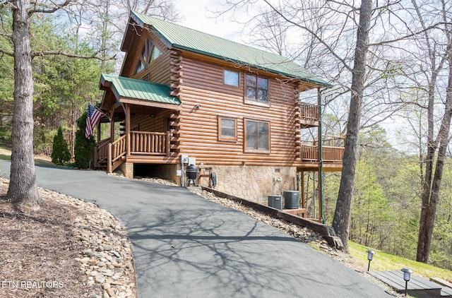 view of side of property featuring metal roof, driveway, central AC unit, and log siding