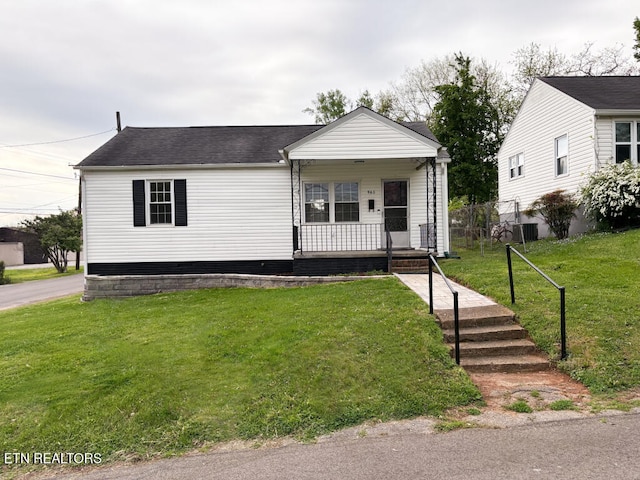 view of front facade with a porch, a shingled roof, a front lawn, and central AC unit