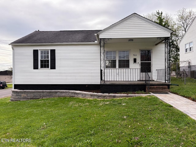 view of front facade with a porch, a front lawn, and a shingled roof
