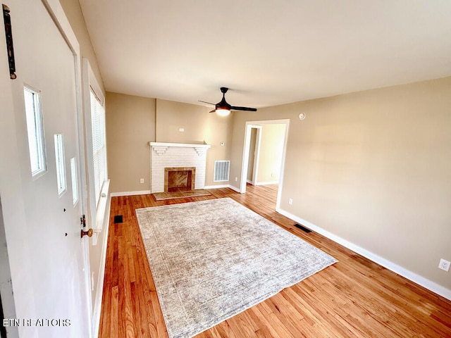unfurnished living room with baseboards, wood finished floors, visible vents, and ceiling fan