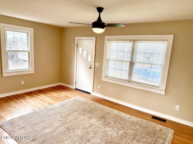 foyer entrance with wood finished floors, visible vents, a ceiling fan, and baseboards