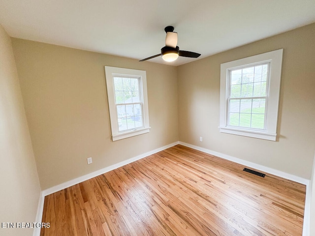 spare room featuring wood finished floors, visible vents, a ceiling fan, and baseboards
