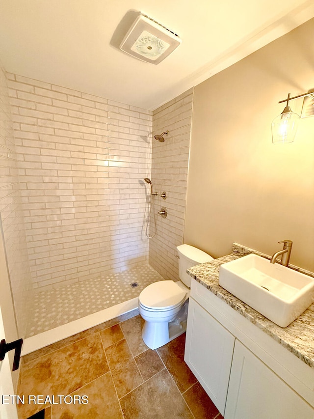 bathroom with toilet, vanity, and tiled shower