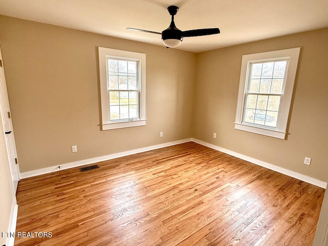 empty room featuring visible vents, baseboards, a ceiling fan, and wood finished floors