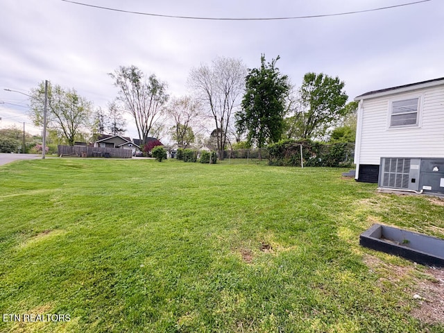 view of yard with central air condition unit and fence