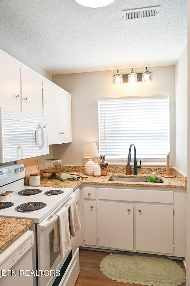 kitchen featuring light countertops, visible vents, a sink, and white appliances