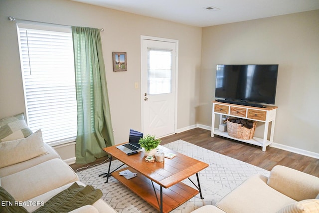 living area featuring wood finished floors, visible vents, and baseboards