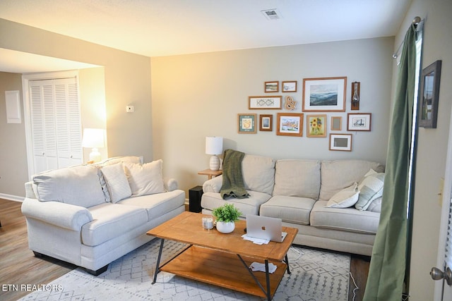 living room with wood finished floors, visible vents, and baseboards
