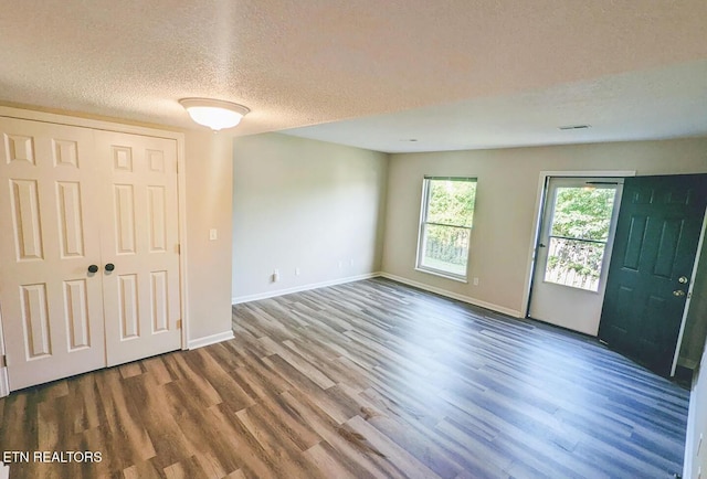spare room featuring a textured ceiling, wood finished floors, and baseboards