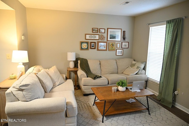 living area with visible vents, light wood-type flooring, and baseboards