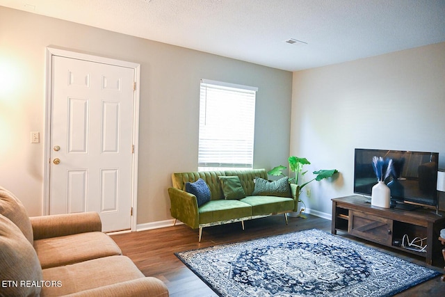 living room featuring baseboards, visible vents, and wood finished floors