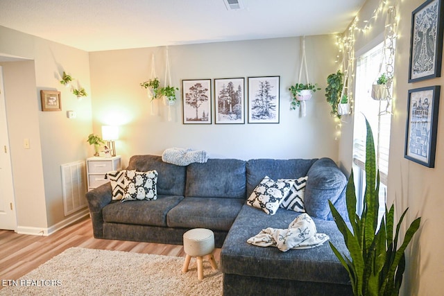 living room with baseboards, visible vents, and wood finished floors