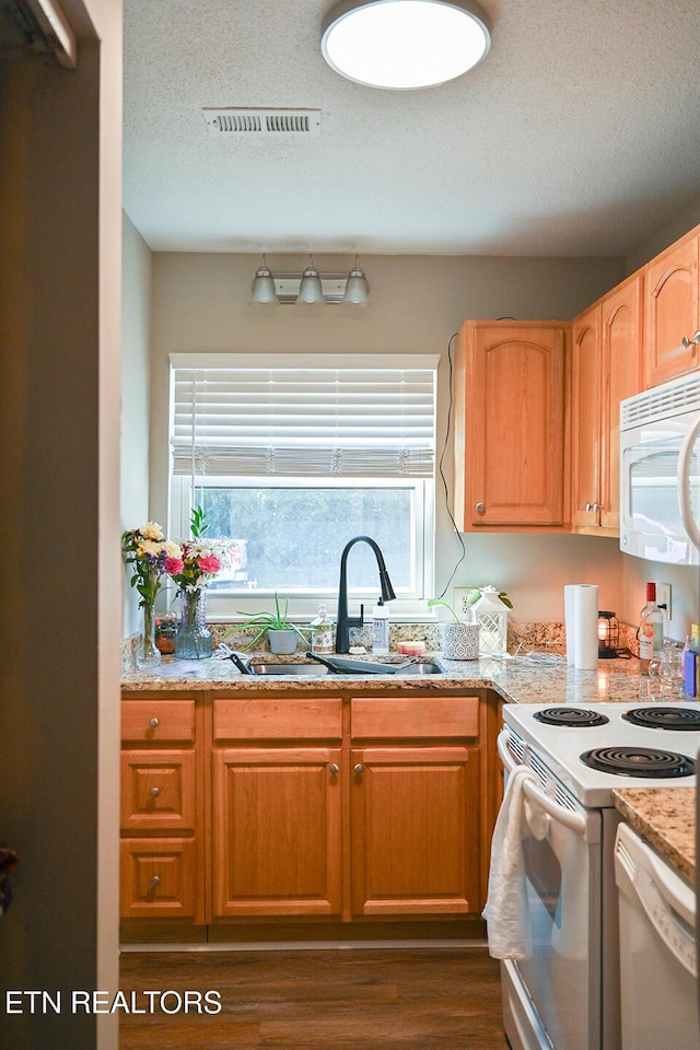 kitchen with a textured ceiling, a sink, visible vents, dark wood-style flooring, and white appliances