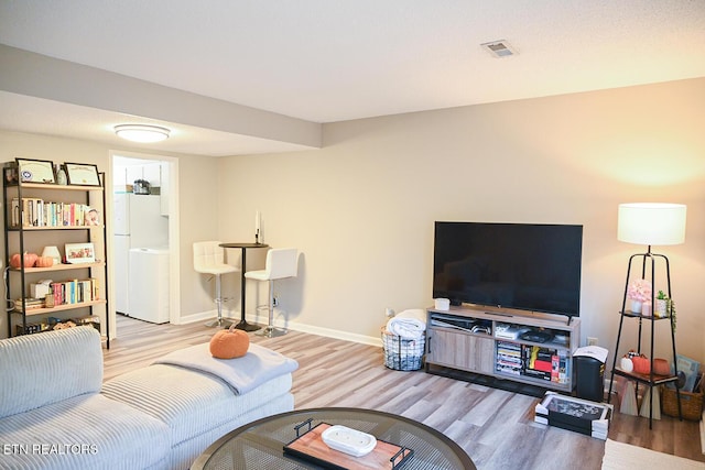 living room with washer / clothes dryer, wood finished floors, and baseboards