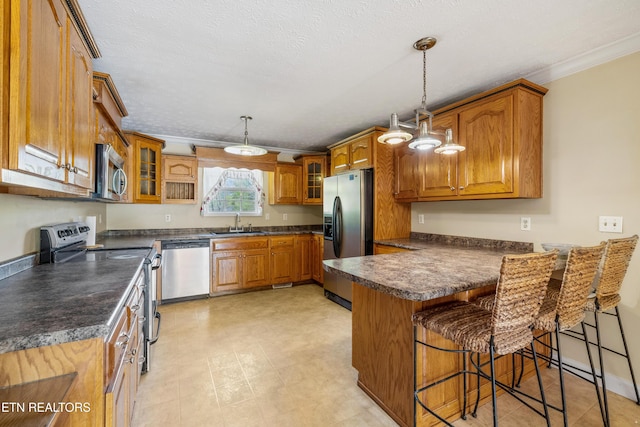 kitchen featuring brown cabinets, a peninsula, stainless steel appliances, and a sink