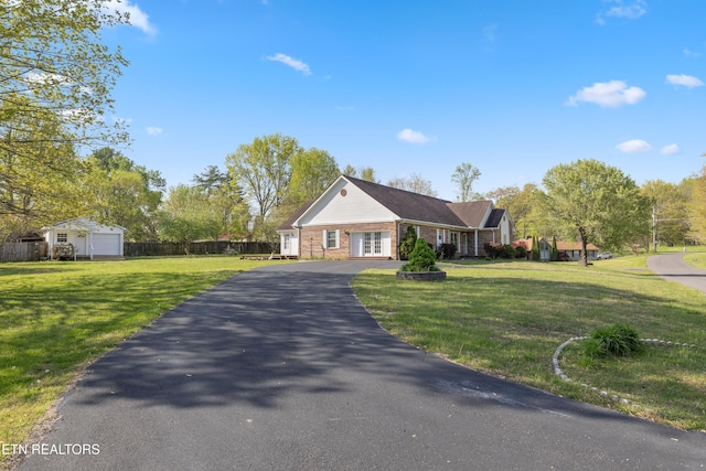 view of front facade featuring a front lawn, aphalt driveway, french doors, fence, and brick siding