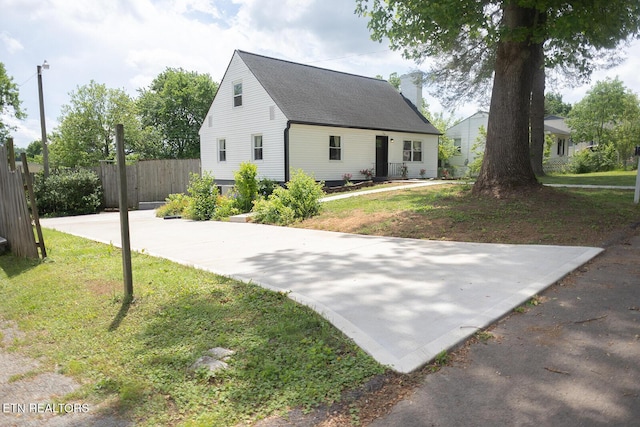 exterior space with a chimney, roof with shingles, fence, and a front yard