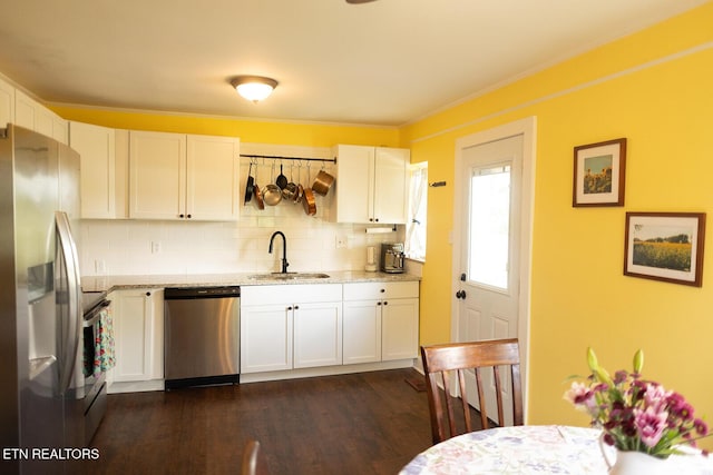 kitchen featuring light stone countertops, white cabinetry, a sink, backsplash, and stainless steel appliances