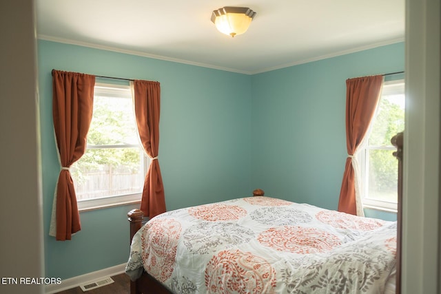 bedroom with baseboards, visible vents, ornamental molding, and wood finished floors