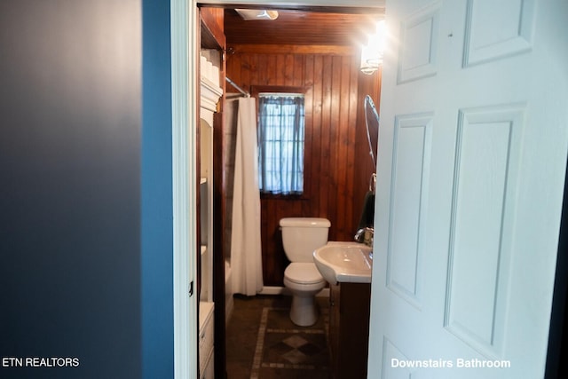 full bathroom with vanity, shower / bath combo with shower curtain, toilet, wooden walls, and wood ceiling
