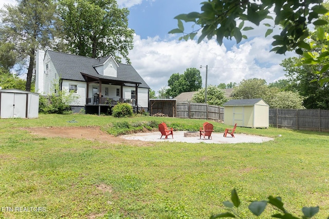view of yard featuring an outbuilding, an outdoor fire pit, a fenced backyard, and a storage shed