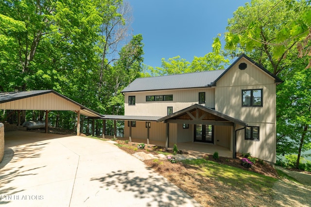 view of front of home with a porch, driveway, french doors, metal roof, and a carport