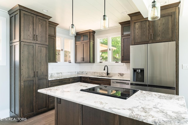 kitchen featuring dark brown cabinetry, glass insert cabinets, a sink, light wood-style flooring, and stainless steel appliances