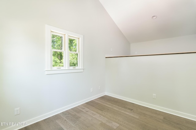 additional living space with baseboards, wood finished floors, and lofted ceiling
