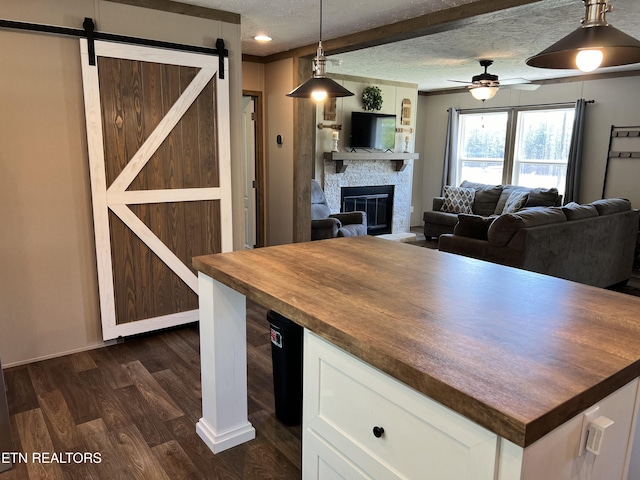 534 Wiggins Rd, Tellico Plains, TN 37385 - kitchen with white cabinets, a fireplace, dark wood-type flooring, butcher block countertops, and a textured ceiling