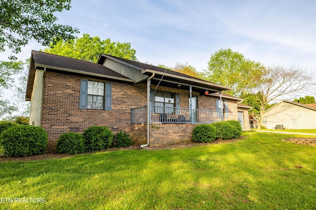 single story home featuring covered porch, a front yard, brick siding, and a garage