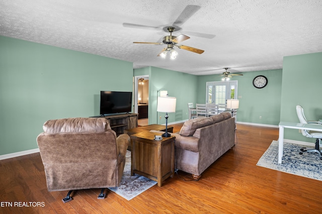 living room with a textured ceiling, wood finished floors, a ceiling fan, and baseboards