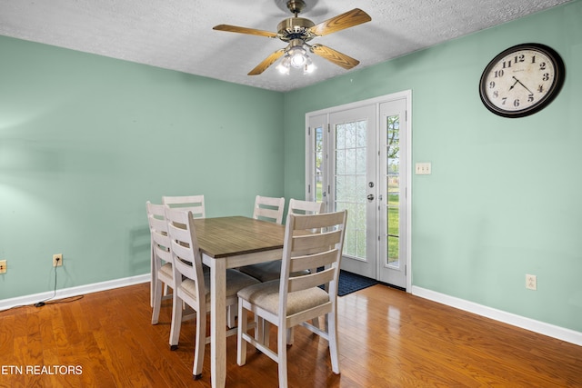 dining space featuring a textured ceiling, wood finished floors, a ceiling fan, and baseboards