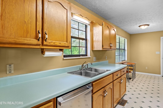 kitchen featuring light floors, light countertops, dishwasher, a sink, and a textured ceiling