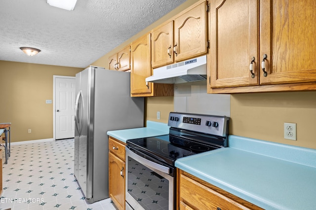 kitchen with a textured ceiling, appliances with stainless steel finishes, light countertops, under cabinet range hood, and light floors