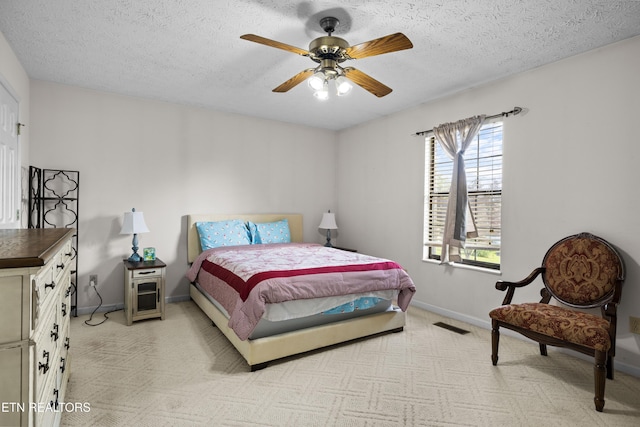 bedroom featuring a textured ceiling, a ceiling fan, light carpet, and baseboards