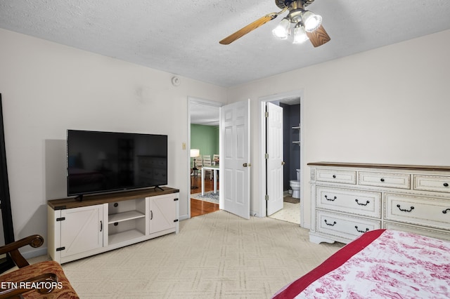 bedroom with a ceiling fan, light carpet, connected bathroom, and a textured ceiling