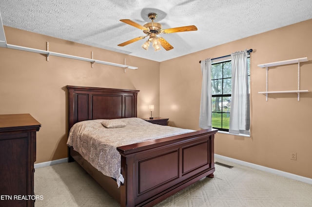 bedroom with baseboards, a textured ceiling, and light colored carpet