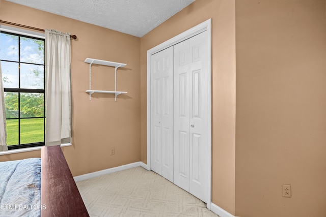 unfurnished bedroom with a textured ceiling, baseboards, carpet flooring, and a closet