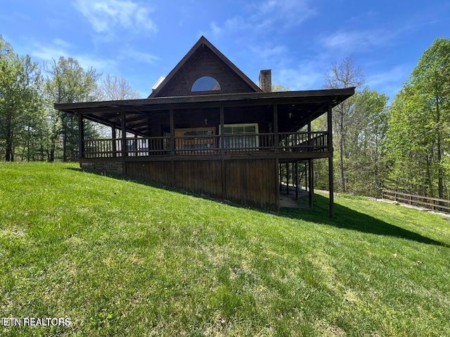 exterior space featuring a wooden deck, a front lawn, and a chimney