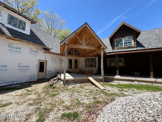 back of property with french doors and roof with shingles