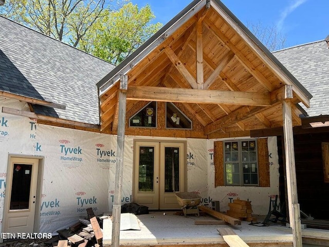 doorway to property featuring french doors and a shingled roof